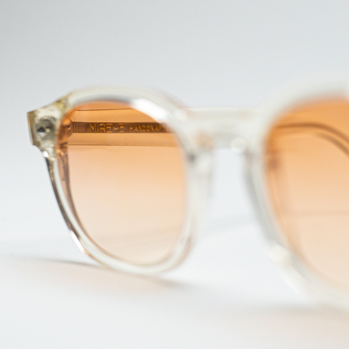 Close-up of Mireye Fire sunglasses in crystal sand, showing ZEISS® lenses with subtle amber tint.
